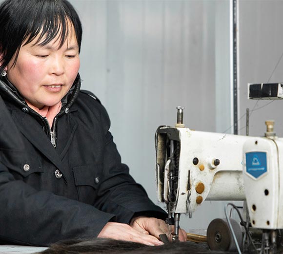 A worker is sewing hair with a machine